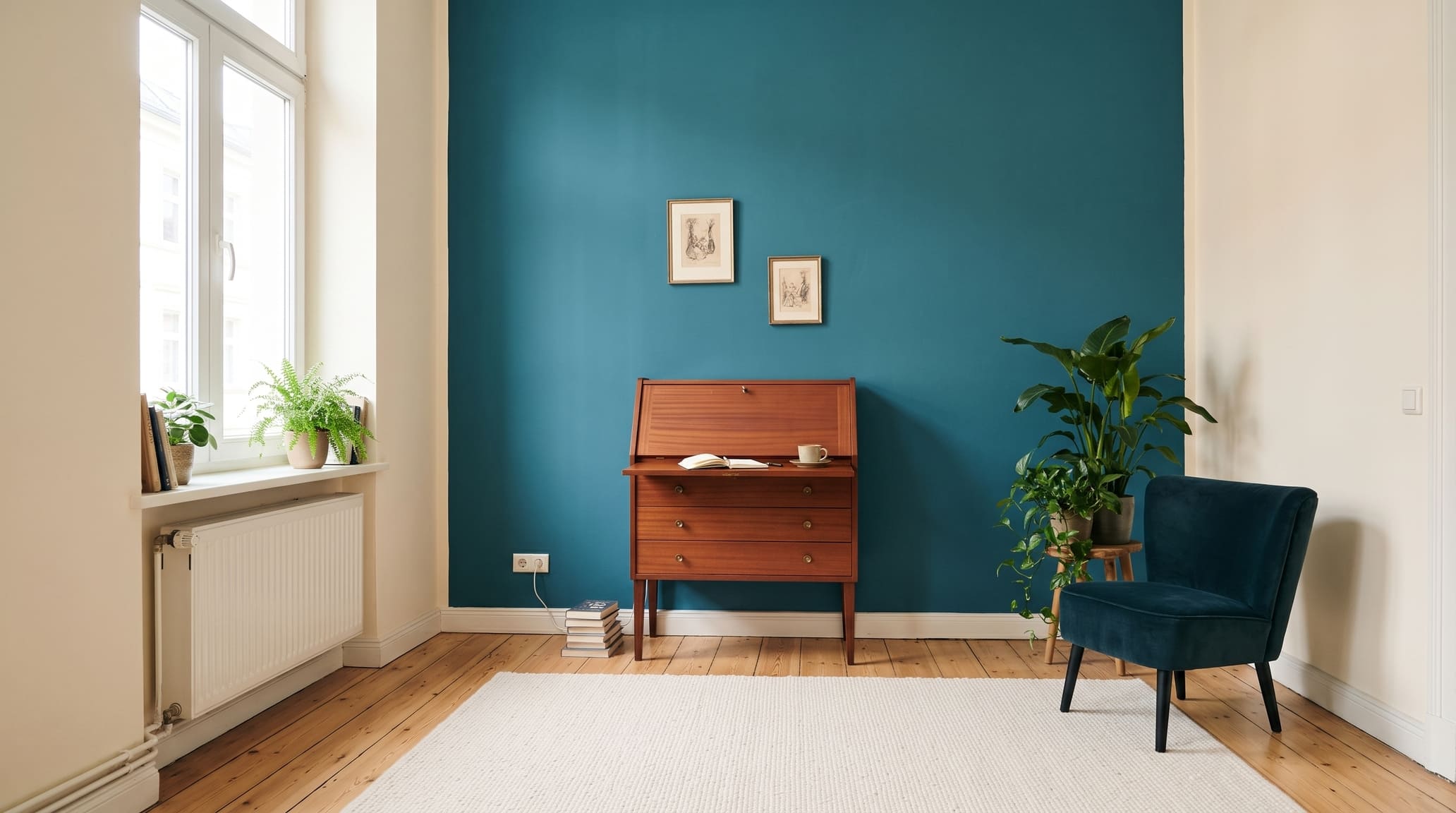 Mahagoni-Sekretär vor einer Wand in Petrol mit Sessel in Blaugrün und hellem Dielenboden